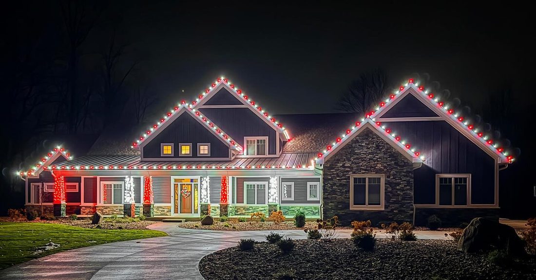 Custom-fit red and white holiday roofline lighting with lit entry columns on a Chicago-area home