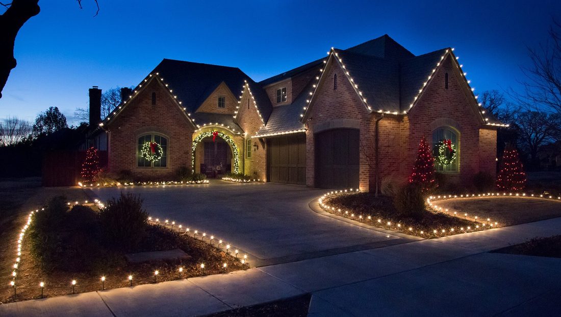 Warm white holiday roofline lighting, wreaths, and landscape lighting at dusk