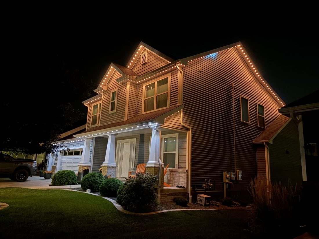Permanent architectural lighting installed along the roofline of a Chicago-area home, warm white mode